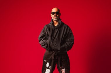 Nucleya performing live on stage with vibrant lights at a music festival, representing his addition to the Lollapalooza India 2026 electronic lineup.