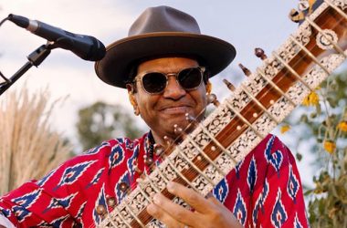 Portrait of Ronobir Lahiri holding a sitar, performing on stage under warm lights, announcing his debut multi-city India tour scheduled for February 2026.